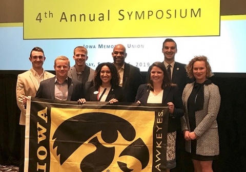 Professionals standing holding an Iowa flag