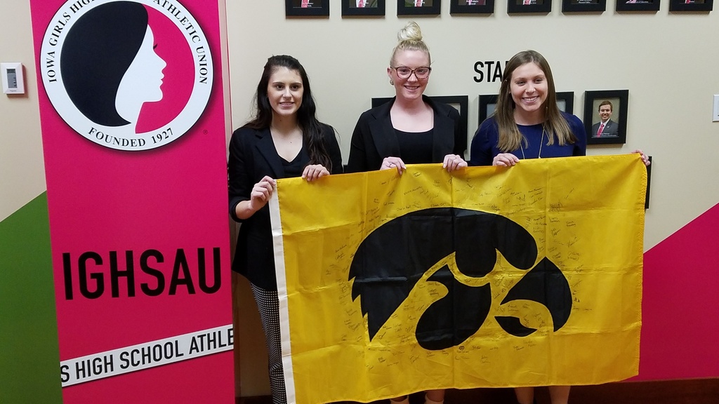 Iowa students at Intercolllegiate event holding a Hawkeye flag